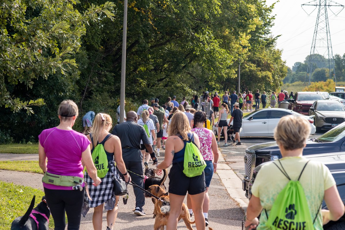 The crowd heading down the walk route with their dogs, green Rescue Network drawstring bags on their backs